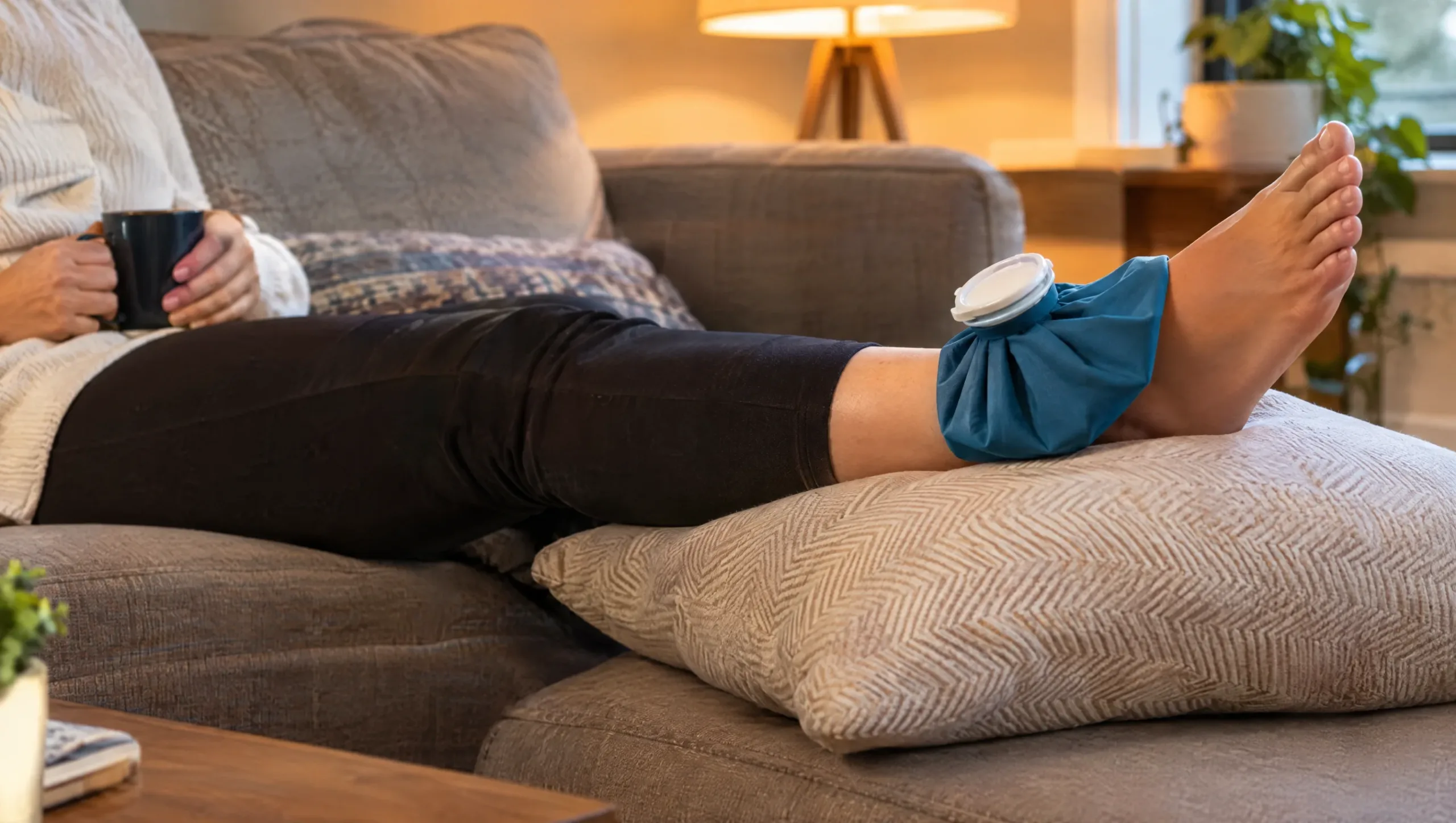 Person resting with an elevated ankle and ice pack at home during early ankle sprain recovery