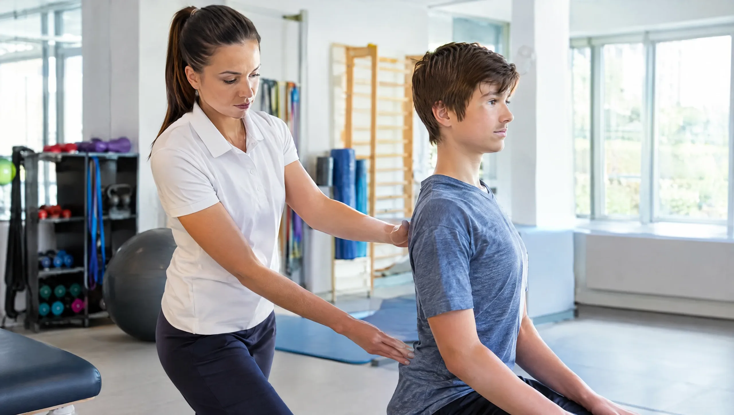 Physiotherapist guiding a teenager through a posture correction exercise