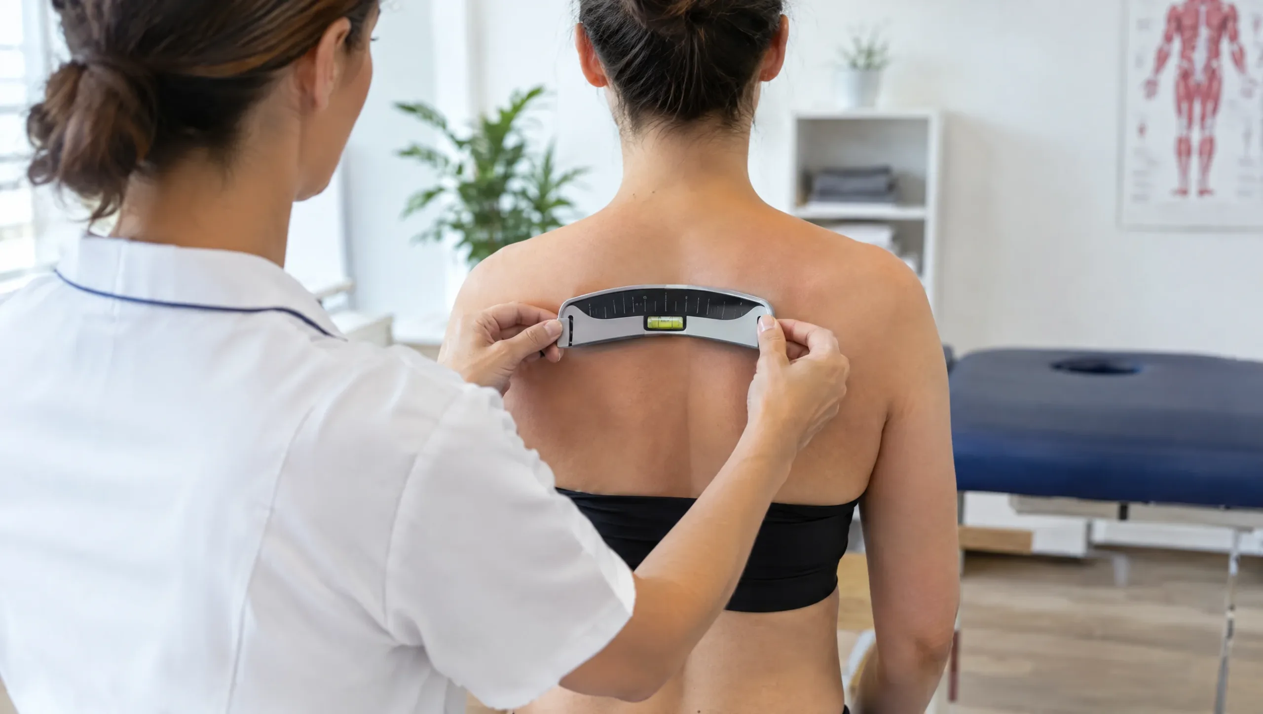 Physiotherapist measuring spinal curve with a scoliometer during a scoliosis assessment