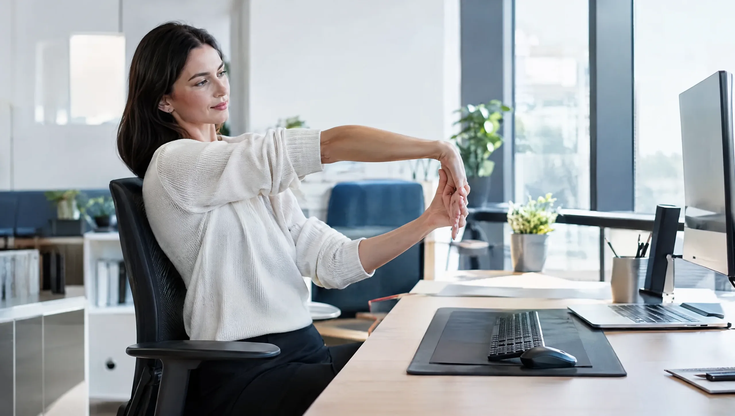 Office worker stretching wrist at an ergonomic desk to help prevent tennis elbow