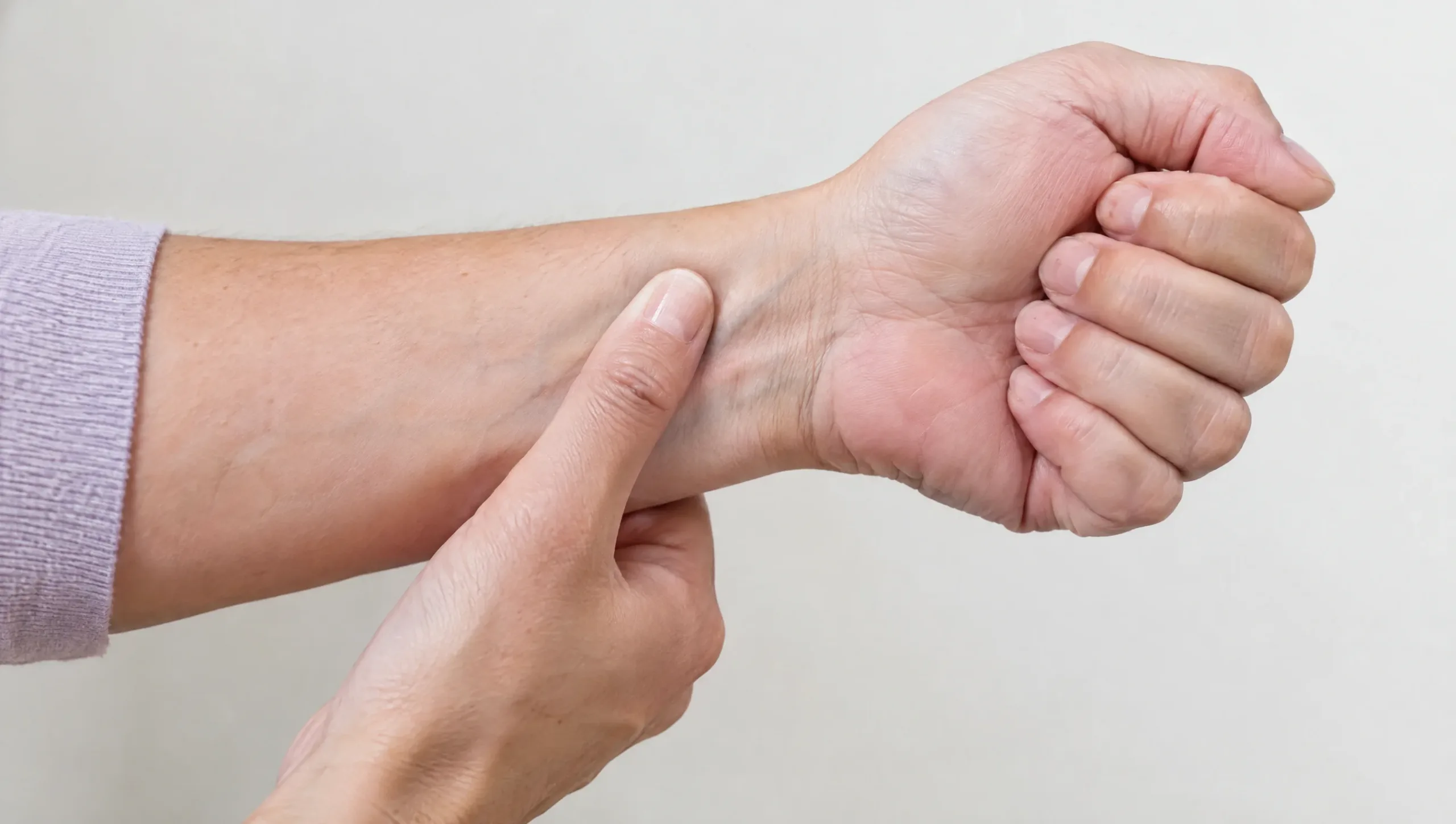 Woman performing a thumb-tuck wrist self-check for De Quervain's tenosynovitis symptoms
